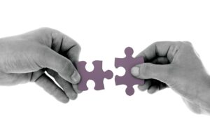 two hands connecting matching puzzle pieces