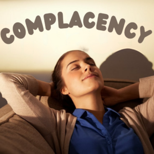 woman relaxing on sofa with shadow word complacency on wall