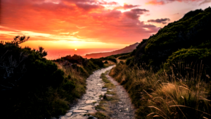 A path winding through difficult terrain leading toward a bright sunrise